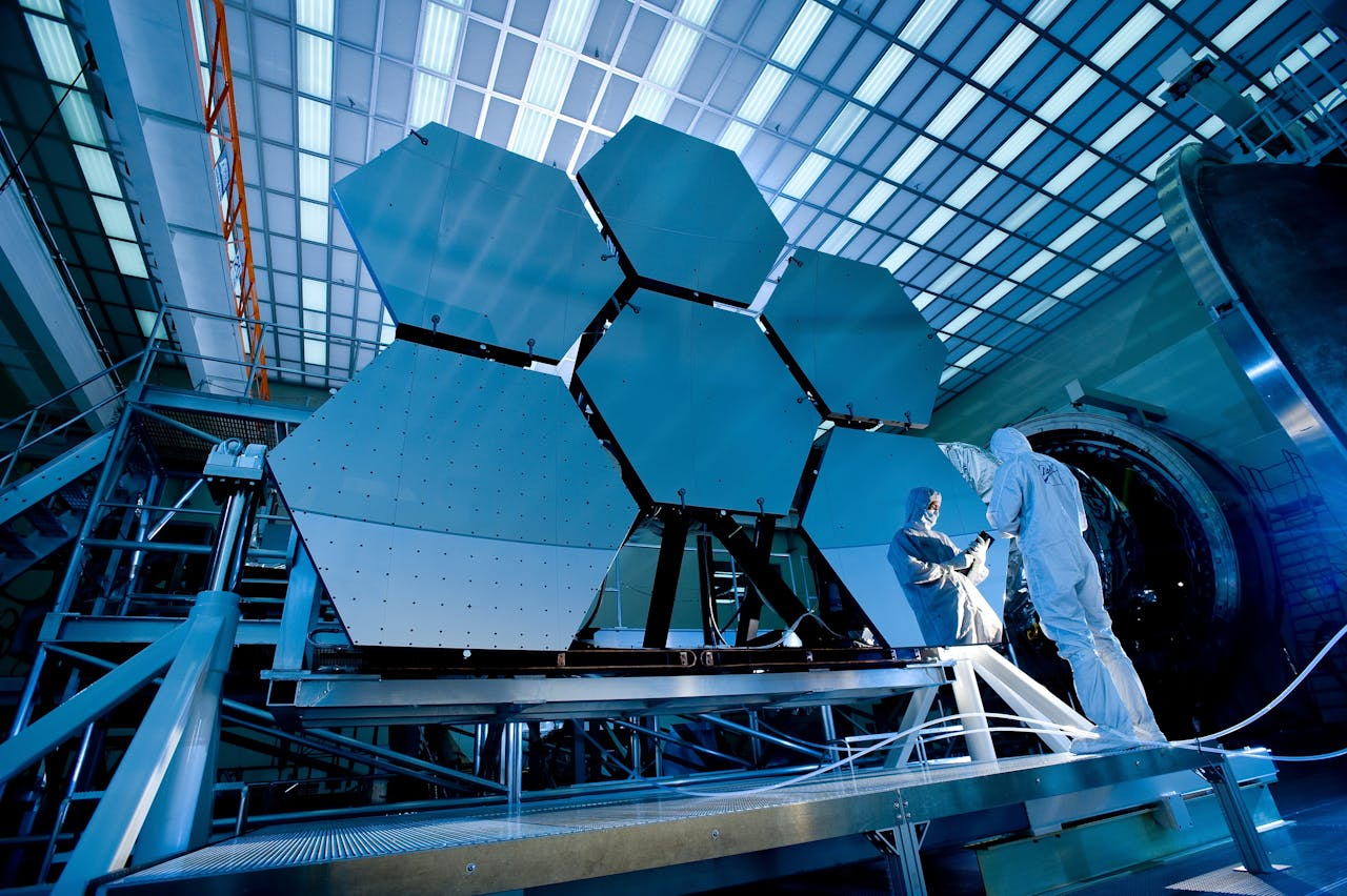 team-04 Engineers in protective suits work on telescopic mirrors in a high-tech lab.