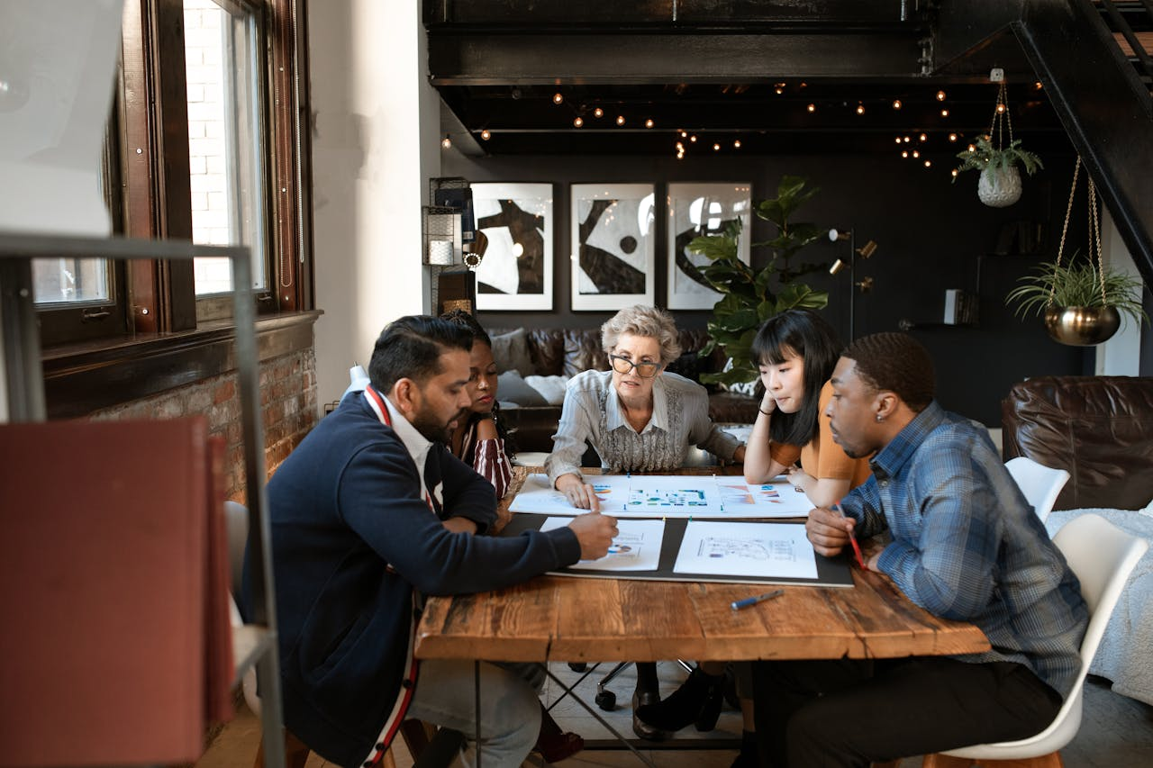 who-we-are A diverse group of professionals brainstorming at a modern office table.